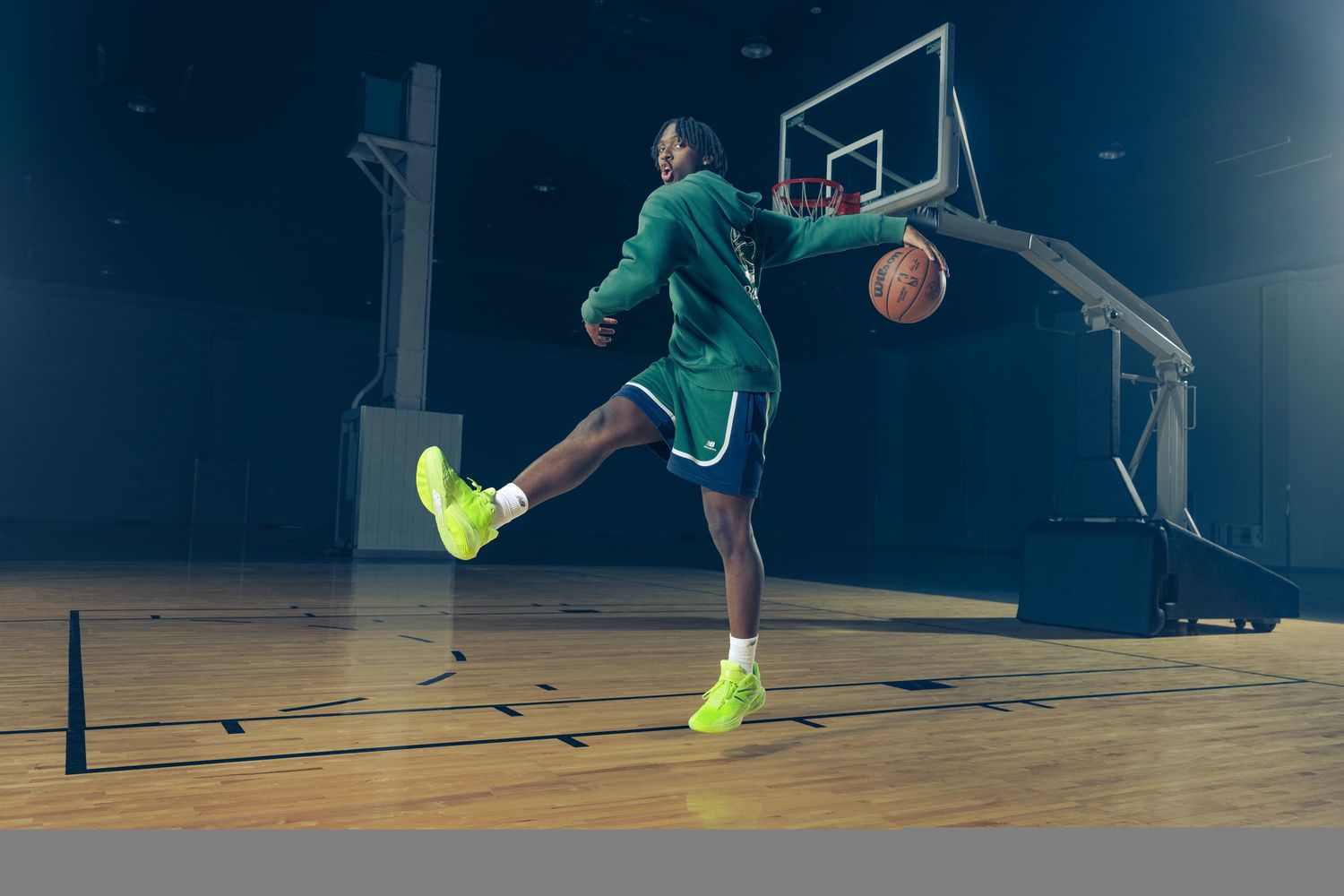 Tyrese Maxey models green New Balance apparel on a basketball court.